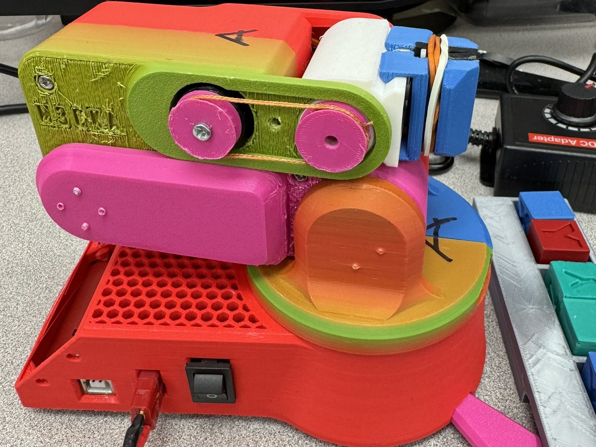 Belt-drive 5-DOF servo arm beside a tray of sorted color blocks